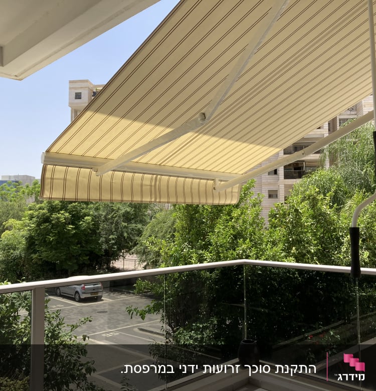 סוכך בד פסים צהוב על מרפסת עם ידית מתכת